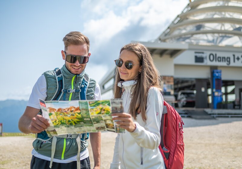 Ein Paar betrachtet gemeinsam eine Wanderkarte vor der Talstation. | © Gianvito Coco