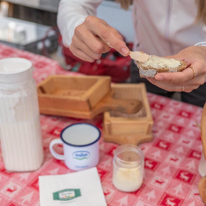 Eine Person beschmiert über einem Tisch ein Brot mit etwas Butter. | © Gianvito Coco